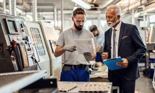 A facility management technician shows documents to an executive.