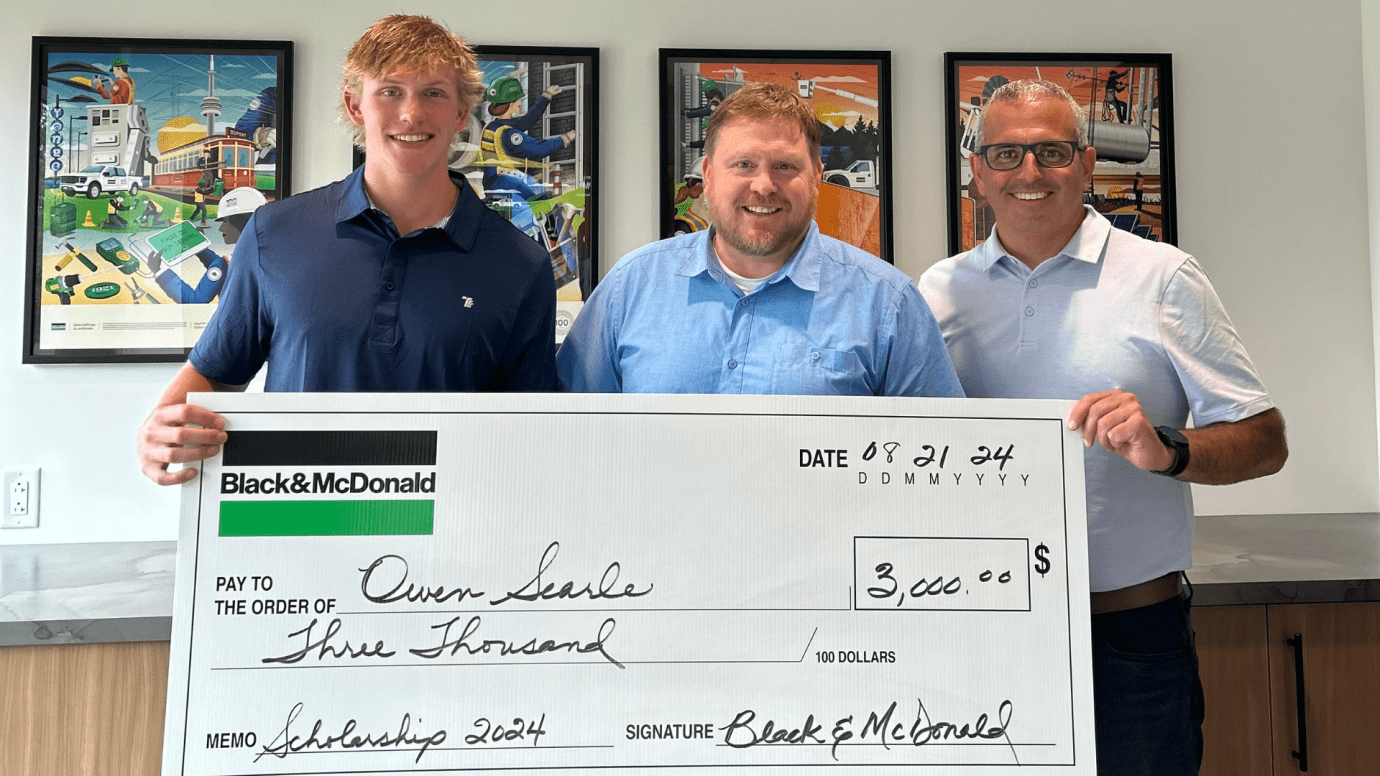 a Scholarship student receiving a novelty cheque from a Black & McDonald employee