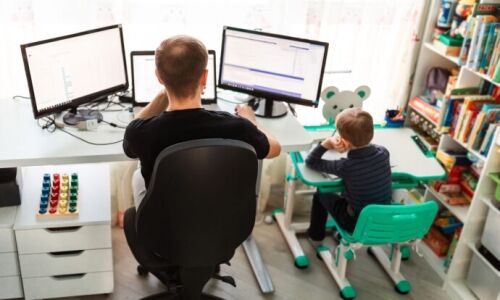 A father and young son working virtually at home side by side.