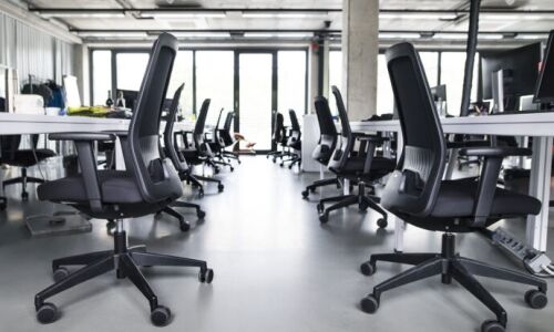 An empty office room filled with chairs, desks, and computers.