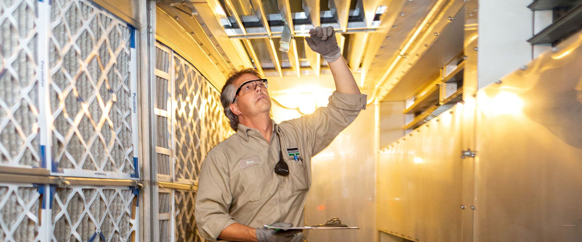 B&M HVAC technician inspecting and replacing filters at a facility.